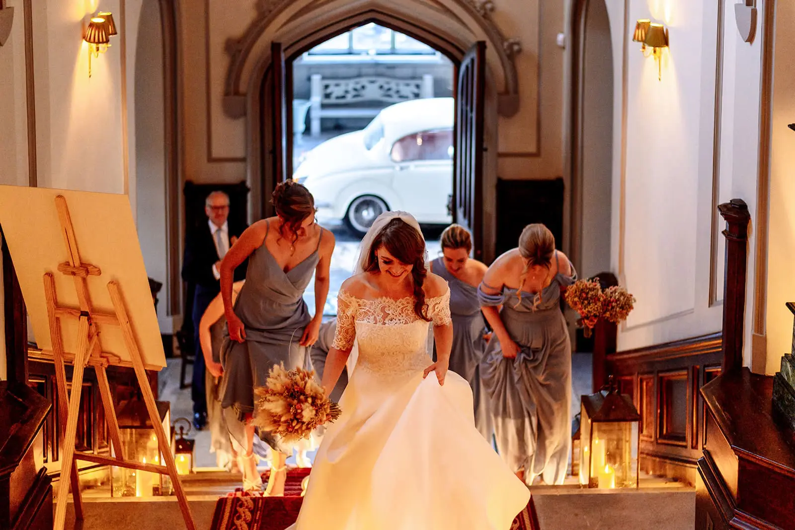 Markree Castle Wedding Photographer - bride walking up the stairs with her bridesmaids on our wedding day the stairs is candlelit